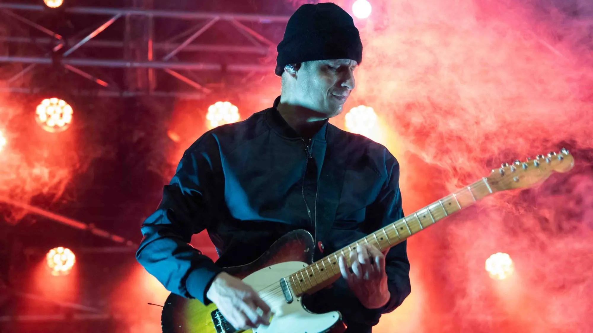 Muziekfotografie van een gitarist in rood licht en rook