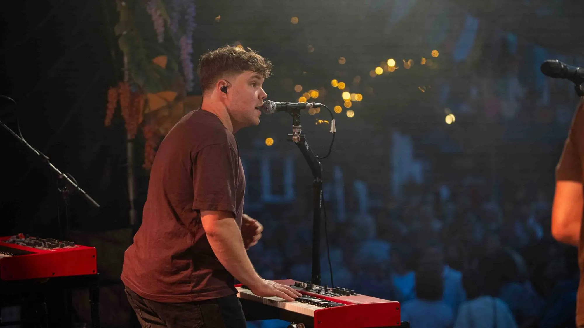 Muziekfotografie van een zingende toetsenist met publiek op de achtergrond
